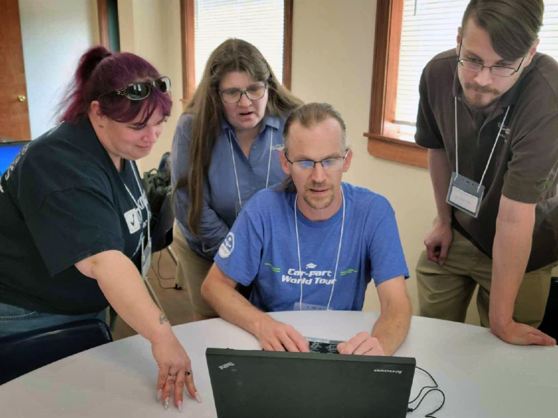 One person working on a laptop computer while three people watch